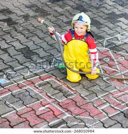 Creative leisure for kids: Funny little boy having fun with fire truck picture drawing with chalk, outdoors