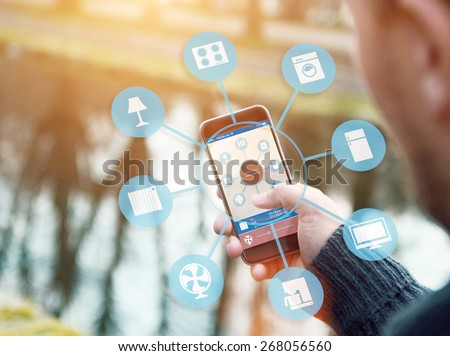 smart house device illustration with app icons. Man in the nature holding his smartphone with smart home app Royalty-Free Stock Photo #268056560