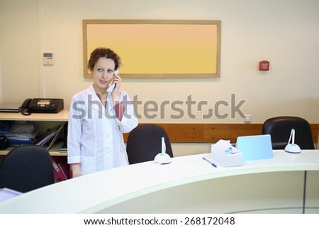 Woman in white coat talking on the phone at the reception