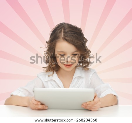 people, childhood, technology and leisure concept - lovely girl holding and looking to tablet pc computer over pink burst rays background
