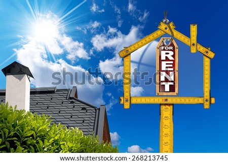 House For Rent Sign - Wooden Meter. Yellow wooden meter ruler in the shape of house and label with text for rent. For rent real estate sign on blue sky with roof, clouds and sun rays
