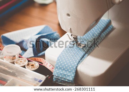 Sewing machine with many sewing utensils on a wooden table