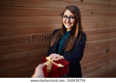 First person portrait with male hand giving saint valentine's gift in heart shape for smiling pretty girl
