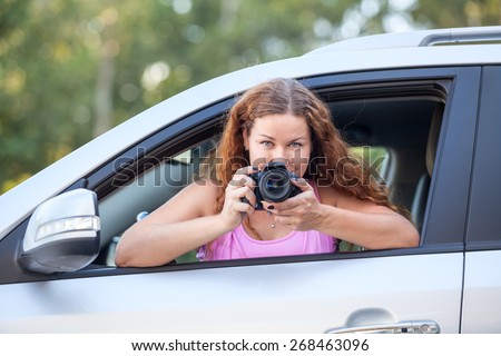 Young woman in pink t-shirt with a camera in hand taking pictures of the car
