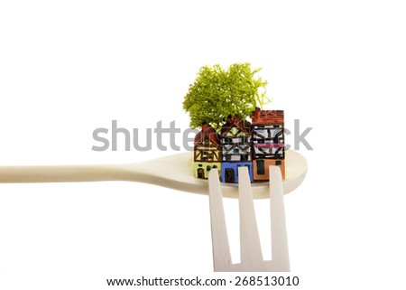 The painted wooden models of typical  buildings of European houses on a small scale with wooden cutlery on a white background. The concept of the traditional cuisine