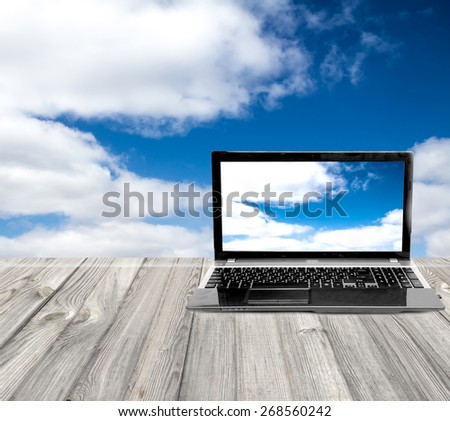 laptop on a wooden table on a background of the sky