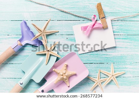 Kids tools for playing in sand  and sea object on turquoise  painted wooden planks. Place for text. Vacation, holiday, summer background. Toned image.
