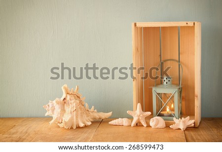 sea shells and lantern on wooden table. vintage filtered image 