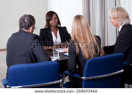 Group of managers interviewing pretty young female candidate for job at the office