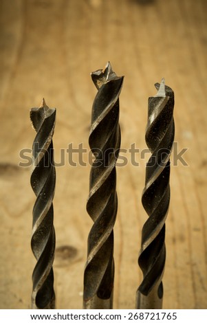 set of used drill bits on wooden table