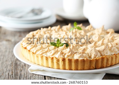 Lemon meringue pie on plate on grey wooden background