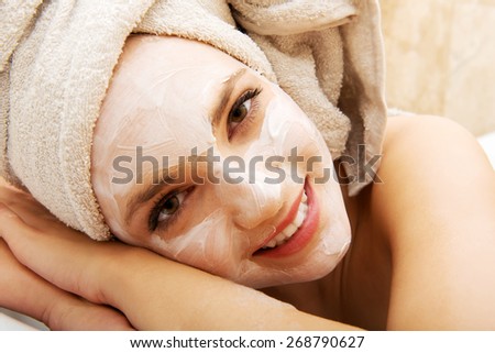 Young spa woman relaxing in bathroom with cream moisturizer. 