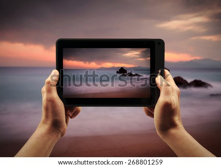 Take a landscape picture with a tablet PC during te sunset 