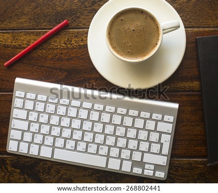 Keyboard, pencil and a Cup of coffee on a dark wooden table, top view.