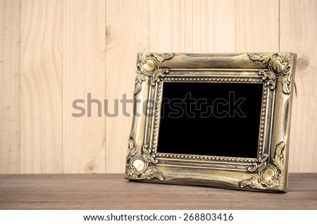 Old picture frame put on wood background. Sepia tone.