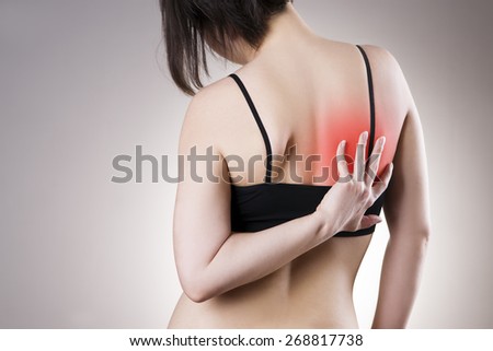 Pain in back of women on gray background. Caring for the female body. Red dot