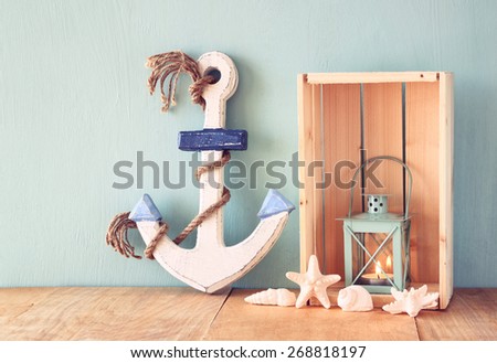 wooden anchor  and lantern on wooden table. vintage filtered image
