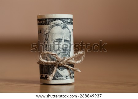 American Fifty Dollar Bills rolled up with a thread on the woode