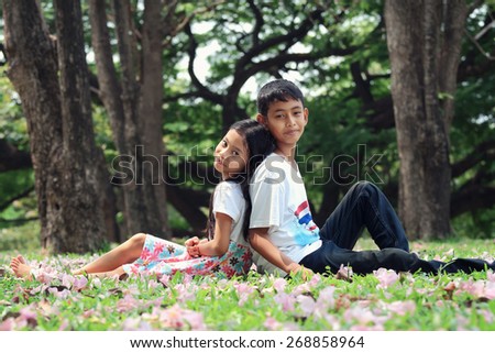 Portrait, asian children sitting on the grass in the park and look at camera