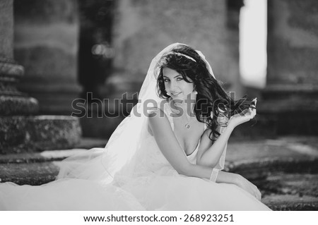 Young bride  posing  against an old church. Wedding picture in black and white. 