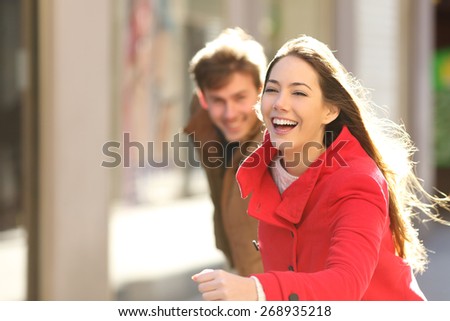 Happy couple running in the street in a sunny day