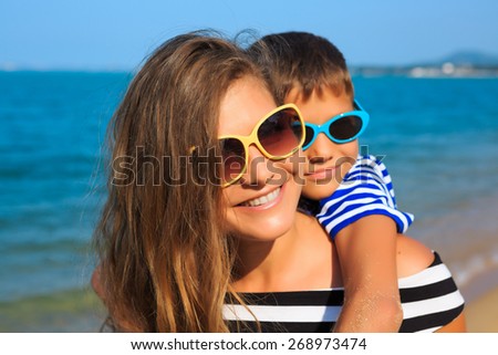 Happy family - mother and son, are playing and laughing on the beach