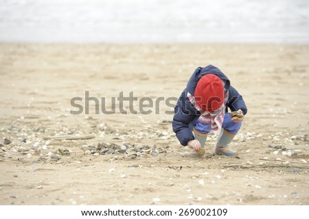 little girl with glasses playing on the beach 