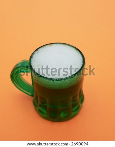 Thick head on green beer on orange background for St. Patrick's Day