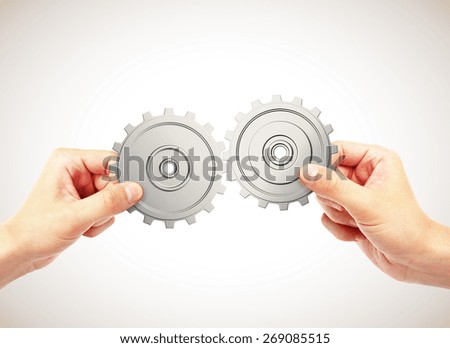 hands connecting gears on a gray background