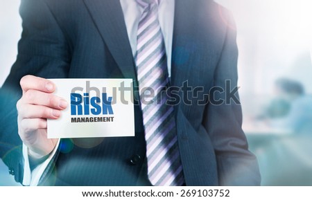 A businessman holding a card with the words, Risk Management, written on it. Instagram styling applied.