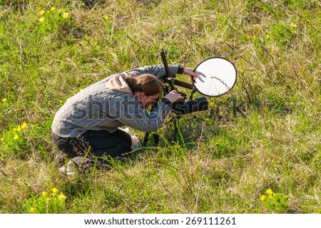 Woman takes a photograph of small flowering Hyacinthella plant in chalk steppe using tripod, professional photo camera and a light diffuser disk