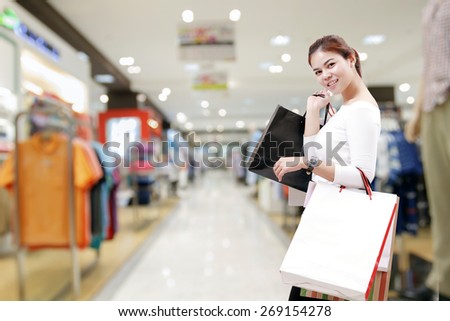 happiness, consumerism, sale and people concept - smiling young woman asian with shopping bags over mall/suppermarket background