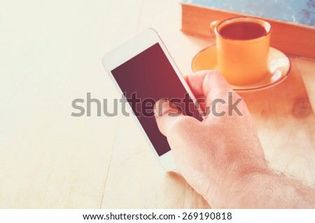man holding smart phone over wooden table background
