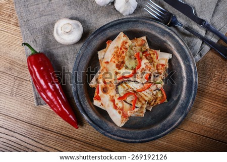 Sliced pizza with chicken, zucchini, eggplant and mushrooms on the plate vintage. Wooden  background