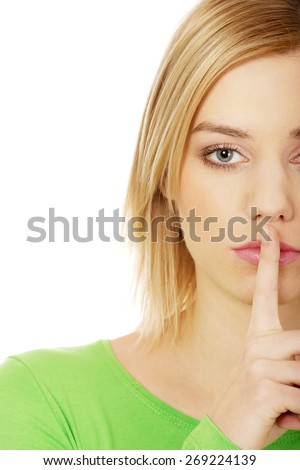 Caucasian woman making hush gesture.