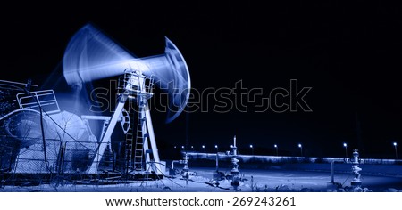 Oil and gas industry. Panoramic of a pumpjack. Night view.