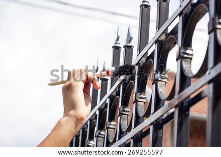 hand with brush painting metal fence  Royalty-Free Stock Photo #269255597