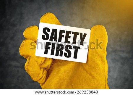 Safety First on Business Card, Male Hand in Yellow Leather Construction Working Protective Gloves Holding Card with Rounded Corners.