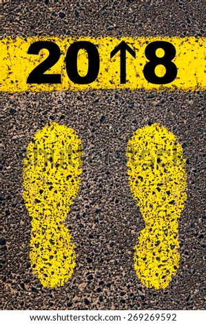 Year 2018 is coming message, number 1 replaced with arrow pointing forward. Conceptual image with yellow paint footsteps on the road in front of horizontal line over asphalt stone background.