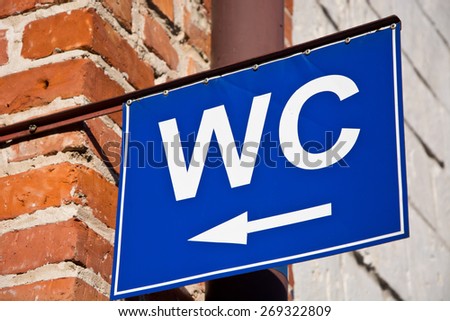 White wc letters and arrow on blue background