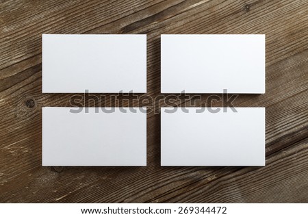 Four stacks of blank business cards on a dark wooden background. Mockup for branding identity. Clipping path. Top view.
