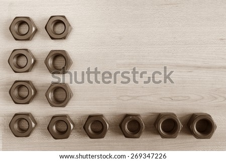 Coated stud bolts and nut isolate on wood texture background 