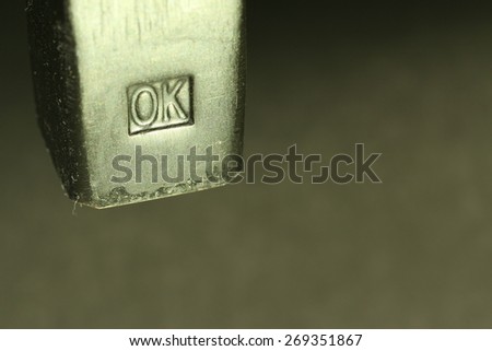 Single ordinary hammer with black heavy steel hammerhead and white metal shine side with quality control stamp sign saying OK, shot as a macro closeup image on dark gradient artistic background