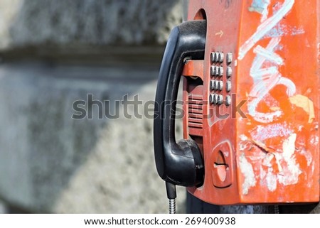 the old red payphone with a black receiver is fixed on a stone wall with a blank space for the text Royalty-Free Stock Photo #269400938