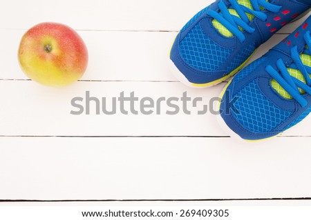 Sport shoes and apple on white wooden background. Top view sport equipment. Selective focus