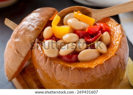 White bean and  red pepper vegetables stew in pumpkin bowls served on wooden board
