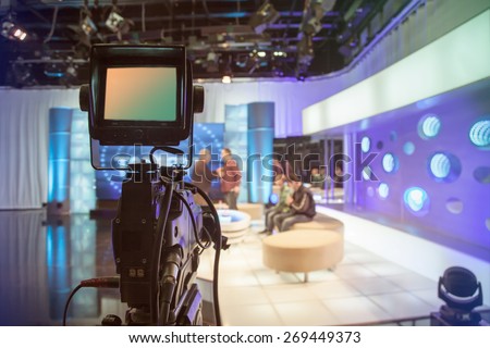 Television studio with camera and lights - recording TV show. Shallow depth of field - focus on camera Royalty-Free Stock Photo #269449373