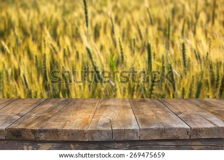wood board table in front of field of wheat on sunset light. Ready for product display montages 