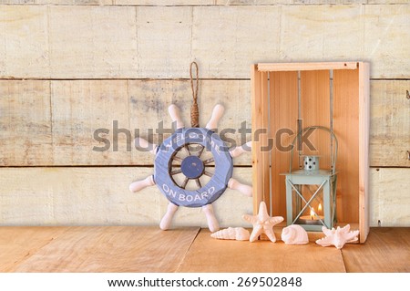 old nautical wood wheel and shells on wooden table over wooden background 