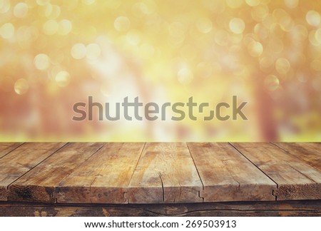 vintage wooden board table in front of dreamy and abstract forest landscape with lens flare. 